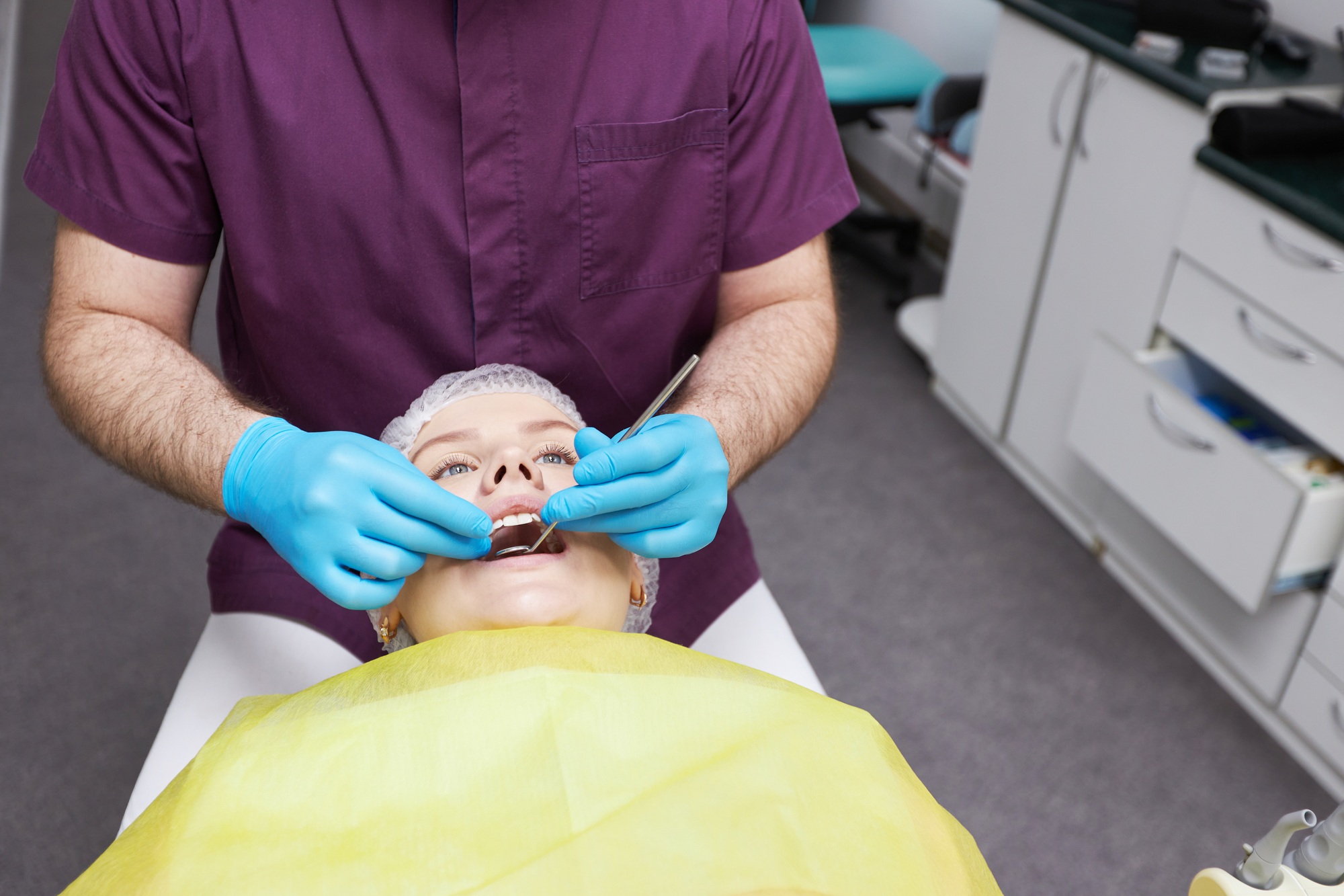 Close-up hands of a male doctor dentist hygienist examining for cavities and gum disease